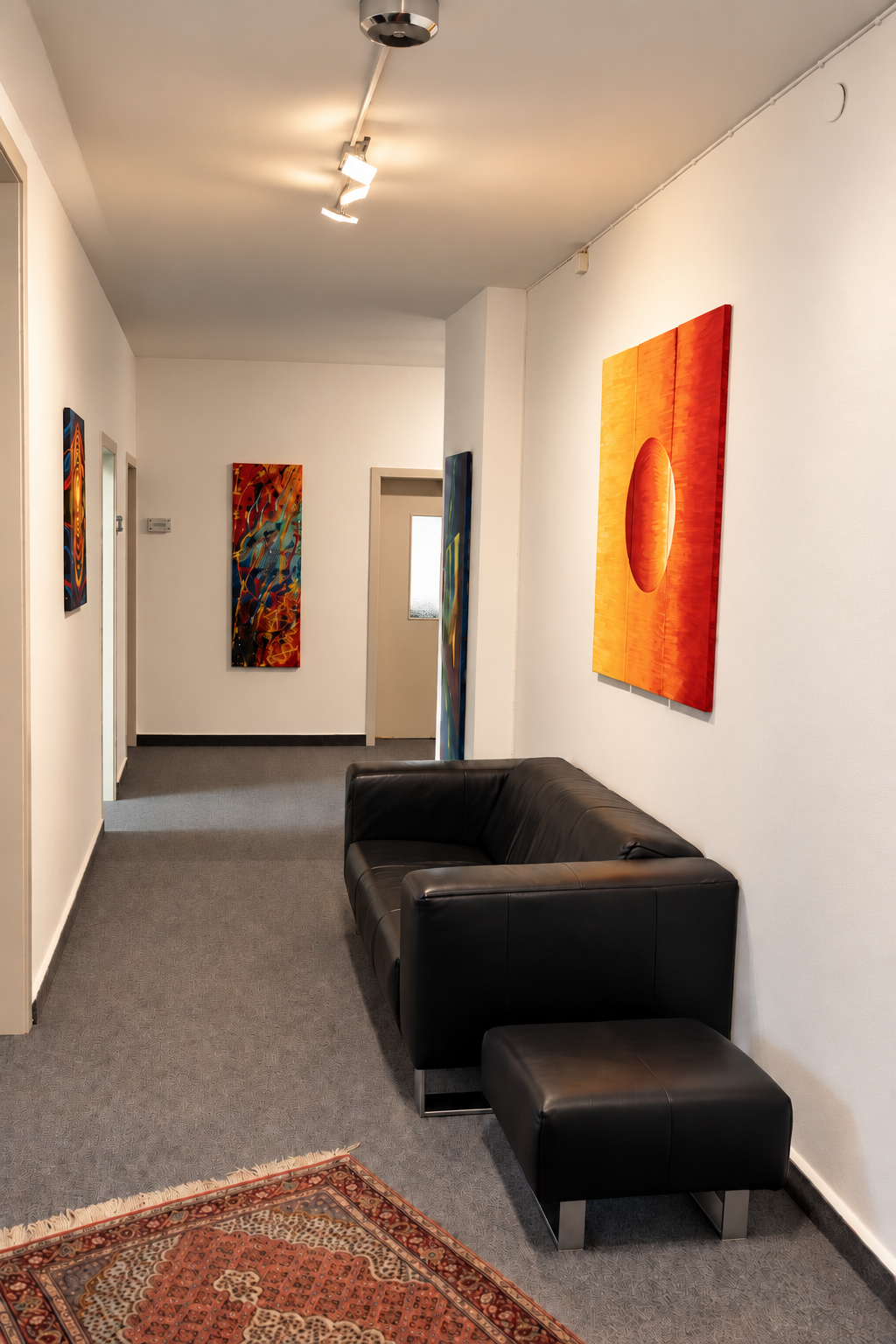 Wartebereich mit schwarzem Sofa und Bildern im Kanzleiflur